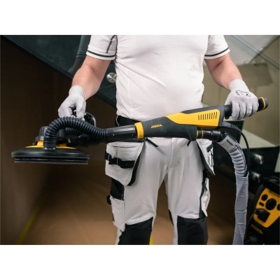 Pessoa segurando lixadora elétrica preta e amarela com texto MIRKA