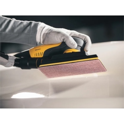 Lixadora elétrica preta e amarelo usada para lixar superfície branca brilhante.