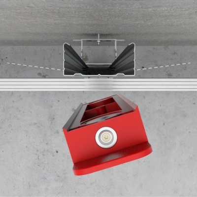 Instalação de ângulo de metal vermelho com nível circular em trilho metálico prateado e suporte preto, sobre superfície cinza.