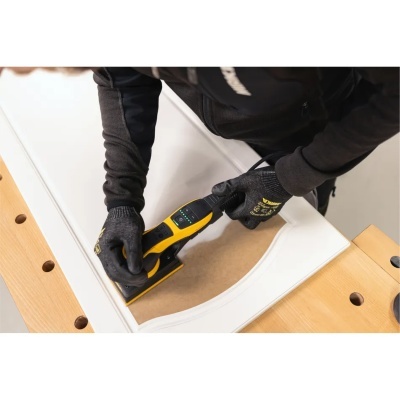 Lixadora elétrica preta e amarela usada numa porta branca sobre uma bancada de madeira