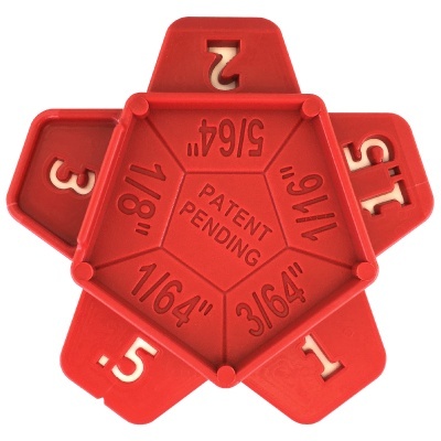 Dispositivo plástico vermelho com medidas em polegadas gravadas.