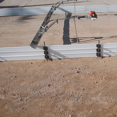 Régua vibratória metálica com motor a gasolina sobre solo arenoso