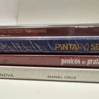 Quatro CDs empilhados com capas e títulos visíveis.