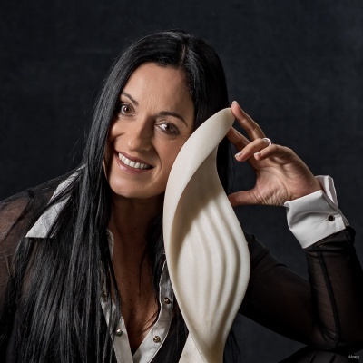 Mulher com escultura branca abstrata ondulada em fundo escuro