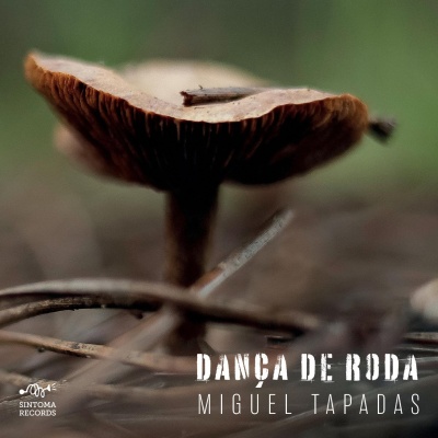 Capa de álbum com cogumelo castanho na floresta e texto branco