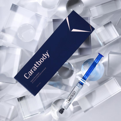 Embalagem azul e seringa do Caratbody sobre superfície com formas geométricas transparentes
