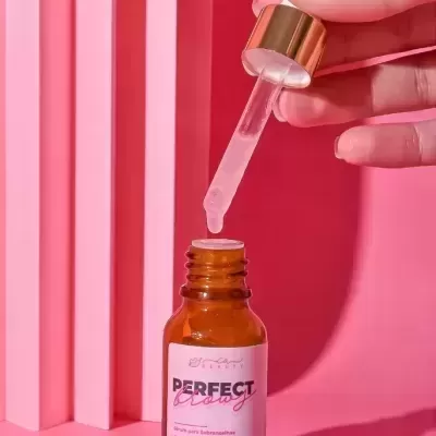 Frasco de vidro âmbar com conta-gotas dourado em fundo rosa