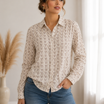 Camisa feminina bege com padrão de laços castanhos e jeans azul em ambiente interior claro.