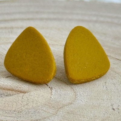 brincos triangulares amarelo mostarda sobre fundo de madeira clara