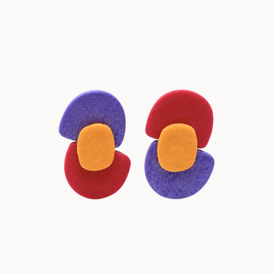 Brincos coloridos em formas arredondadas vermelho, roxo e amarelo com textura irregular