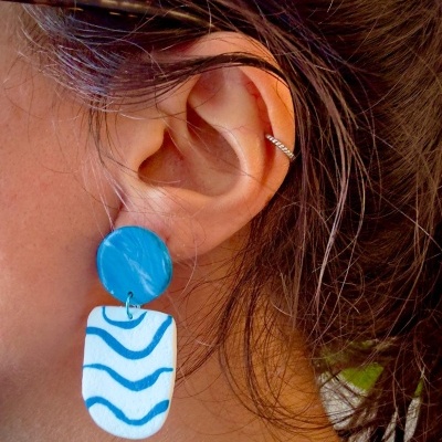 Brinco azul e branco com padrão ondulado usado na orelha