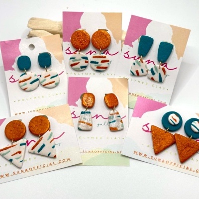Seis pares de brincos de argila polimérica coloridos em cartões de marca