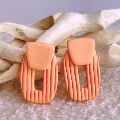 Brincos de argola coral com textura estriada e superfície lisa