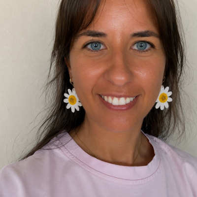 Brincos flor margarida branco e amarelo usados por mulher