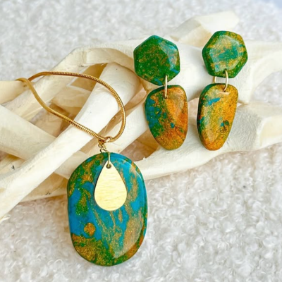 Conjunto de joias com colar e brincos em resina azul e dourada com padrão marmoreado e detalhes em metal dourado