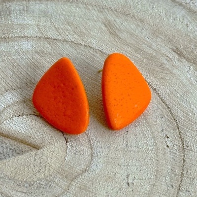 Brincos laranja em resina ou plástico sobre superfície de madeira clara