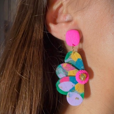 Brinco pendente colorido em forma de flor com pétalas pintadas e botão central rosa.