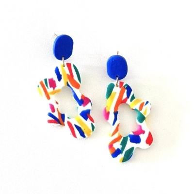 Brincos coloridos com tachas azuis e pendentes multicoloridos em fundo branco