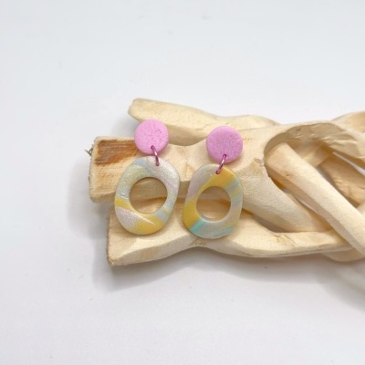Brincos ovais coloridos com bases redondas cor-de-rosa sobre madeira