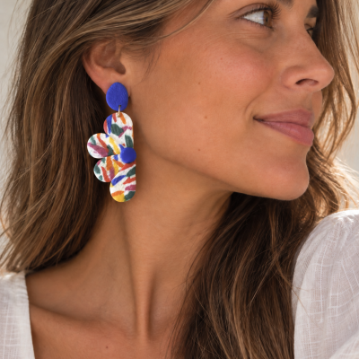 Brincos pendentes coloridos com padrão abstrato usados por mulher
