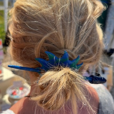 Alfinete de cabelo azul e verde em forma de estrela do mar num cabelo loiro.