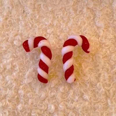 Dois bastões de doces vermelhos e brancos sobre superfície cremosa texturada