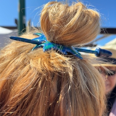 Presilha azul segura cabelo loiro em coque ao ar livre