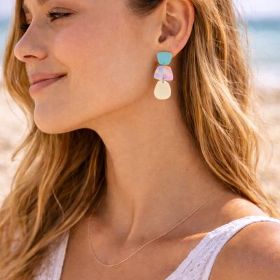 Brincos pendentes coloridos usados por mulher na praia