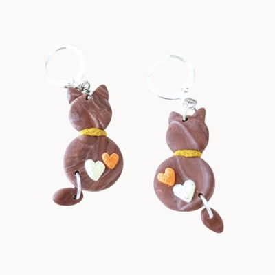 Brincos de gato castanhos com coroa amarela e corações em argolas prateadas