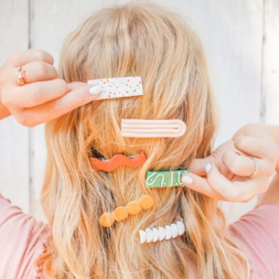 Presilhas de cabelo coloridas em cabelo loiro com fundo de madeira clara