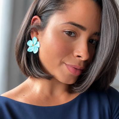 Brincos flor azul em mulher com cabelo castanho e vestido azul
