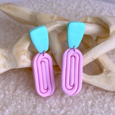 Brincos pendentes azul celeste e rosa em fundo branco e madeira