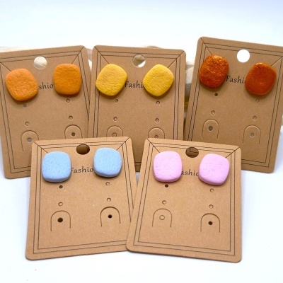 Brincos quadrados coloridos em cartões castanhos