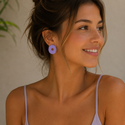 Brincos redondos lilás usados por mulher com top lilás e cabelo apanhado