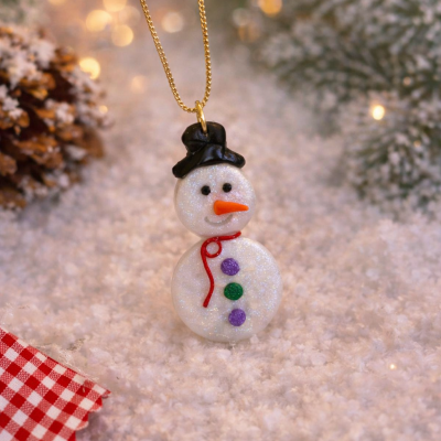 Colar com pendente de boneco de neve brilhante sobre neve artificial