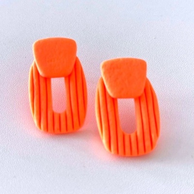 Brincos laranja geométricos com ranhuras em fundo branco