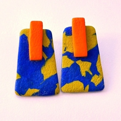 Par de brincos trapezoidais azul, amarelo e laranja com textura, fundo branco