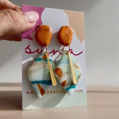 Brincos pendentes coloridos com barras metálicas douradas em cartão de apresentação