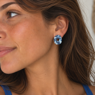 Brincos redondos azul e branco usados por mulher com cabelo castanho.