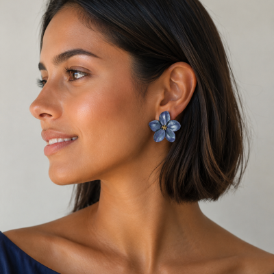Brincos flor azul com centro dourado usados por mulher com vestido azul
