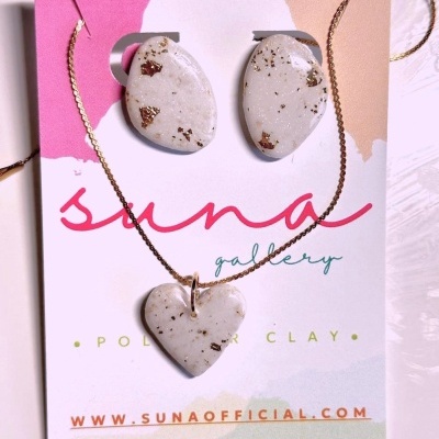 Conjunto de colar e brincos em argila polimérica branca com reflexos dourados em cartão colorido.