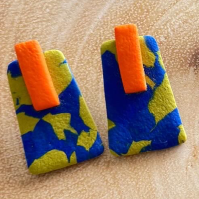 Brincos retangulares azul, amarelo e laranja em superfície bege