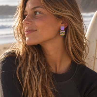 Mulher com brincos coloridos e fato de surf preto na praia