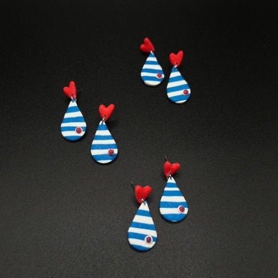 Três pares de brincos com padrão às riscas e corações vermelhos