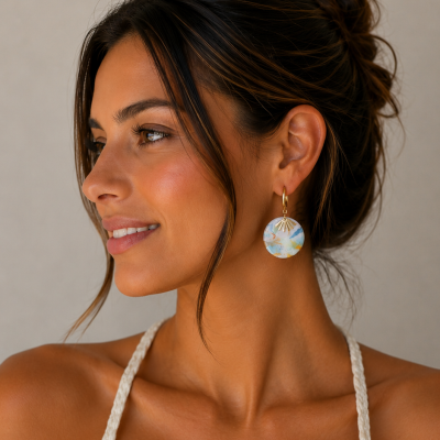 Brincos pendentes redondos em tons claros azuis e amarelos com gancho dourado em mulher com cabelo apanhado