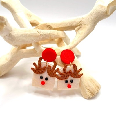 Brincos de rena vermelhos e cor de salmão pendurados em galhos de madeira branca