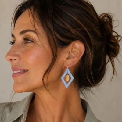 Brinco losango azul pendurado na orelha de perfil de mulher com cabelo preso