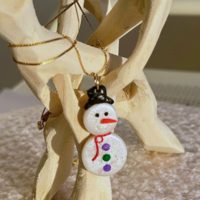 Colar com pendente boneco de neve brilhante pendurado numa estrutura de madeira
