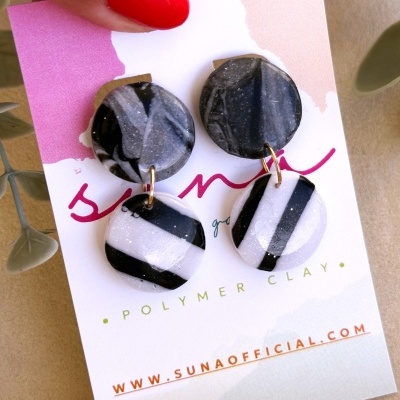 Brincos pretos e brancos em clay polimérico sobre cartão de apresentação