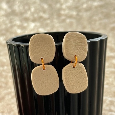 Par de brincos bege pendentes em copo preto canelado